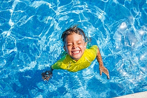 kid with yellow shirt swimming in vinyl pool